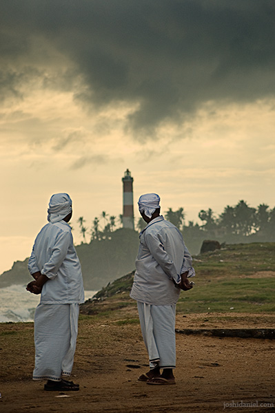Two men looking at passing dark clouds over lighthouse in Vizhinjam, Trivandrum