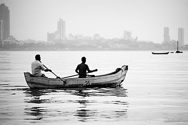 Two fishermen in boat wading through the waters near Mahim in Mumbai