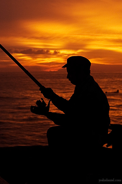 Silhouette of a man fishing at Valiathura pier at twilight