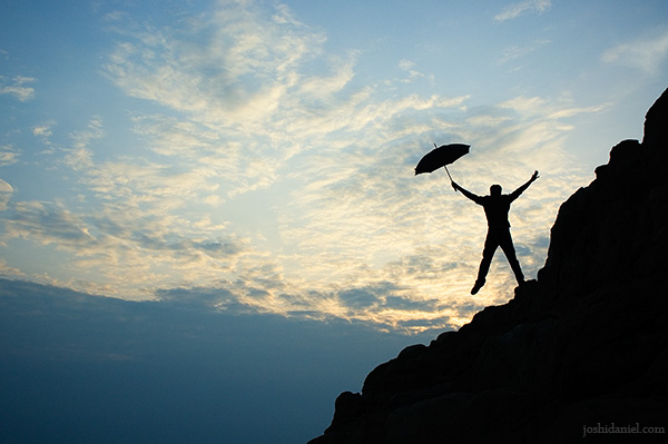 Silhouette of a guy jumping with umbrella