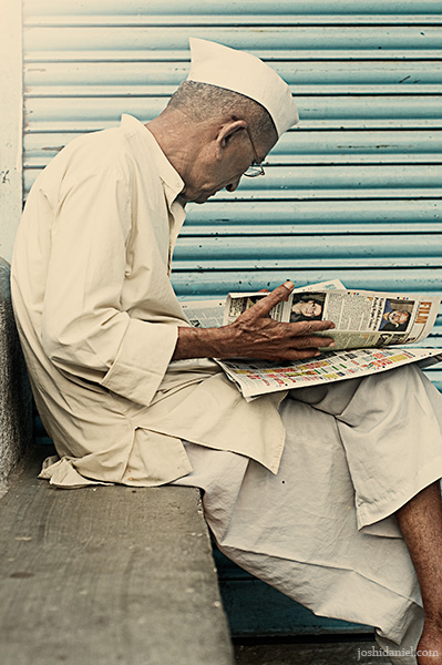 Marathi man with topi reading newspaper