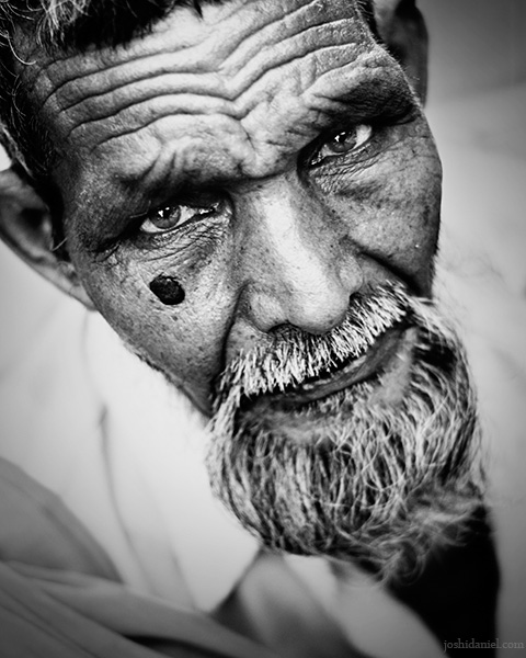 Black and white portrait of an old man with beard looking up from Mumbai