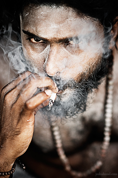 Portrait of Abilash Thankan engulfed in swirls of cigarette smoke