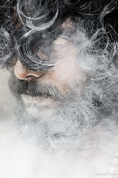 Portrait of Abilash Thankan peering through ash smeared hair