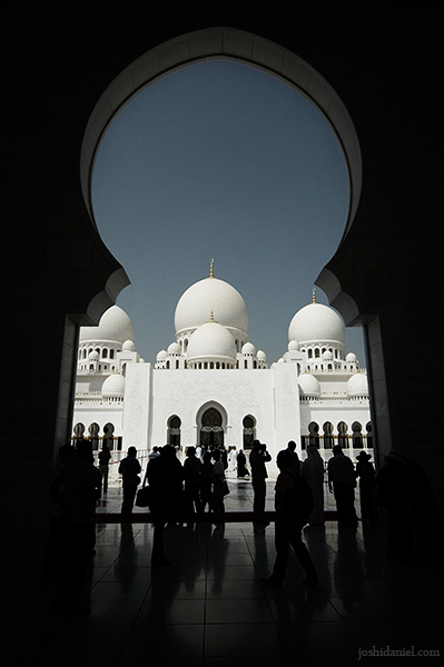 Silhouette of visitors through the arch of Sheikh Zayed Grand Mosque in Abu Dhabi