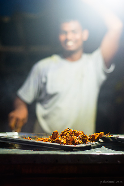 A smiling young man frying crabs at Elliot's Beach, Chennai