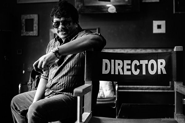 Black and white portrait of actor-director Parthiban Radhakrishnan sitting next to a director's chair