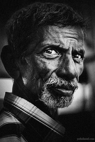 Black and white portrait of an old man at Marina Beach, Chennai with a furrowed look