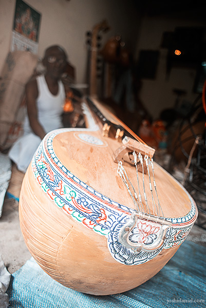 Photo of an old man in his musical instrument shop in Mylapore, Chennai, holding a Veena