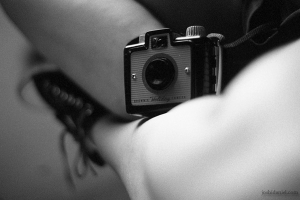 Black and white photograph of a vintage Kodak Brownie Holiday camera nestled between a girl's legs taken on a Nikon FM camera with a Kodak Professional Tri-X 400 Black and White Negative Film
