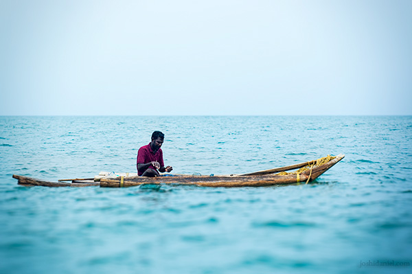 A fisherman fishing from his catamaran in the middle of the sea in Tamil Nadu, India