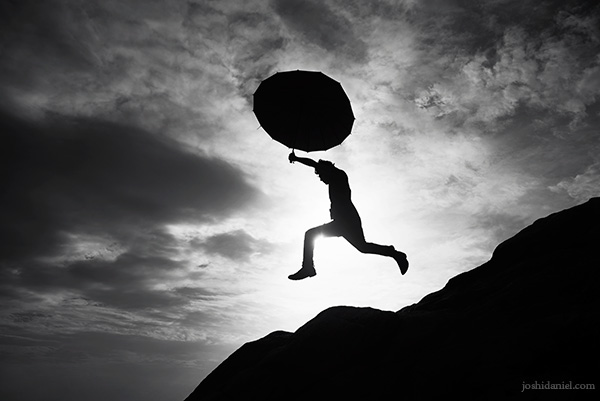 Black and white silhouette of Abilash Thankan leaping with an umbrella in his hand in Trivandrum, Kerala