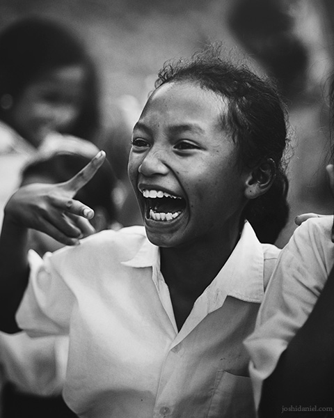 Black and white portrait of a smiling young girl at Taman Bacaan Pelangi (Rainbow Reading Gardens) in Melo Village in Flores, Indonesia