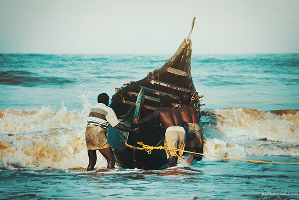 A group of fishermen pushing out a boat at Shankhumugham beach in Trivandrum, Kerala, India