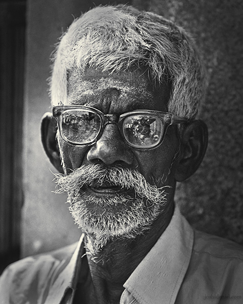 Black and white portrait of an old man from Mylapore wearing spectacles
