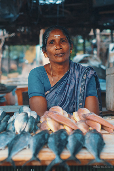 Portrait of a smiling fishmonger lady with the fish laid out in front her at Besant Nagar beach in Chennai, India