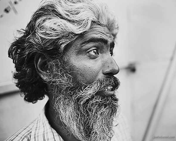 Mid conversation A 28mm wide angle black and white portrait of a bearded man talking in Trivandrum, Kerala, India