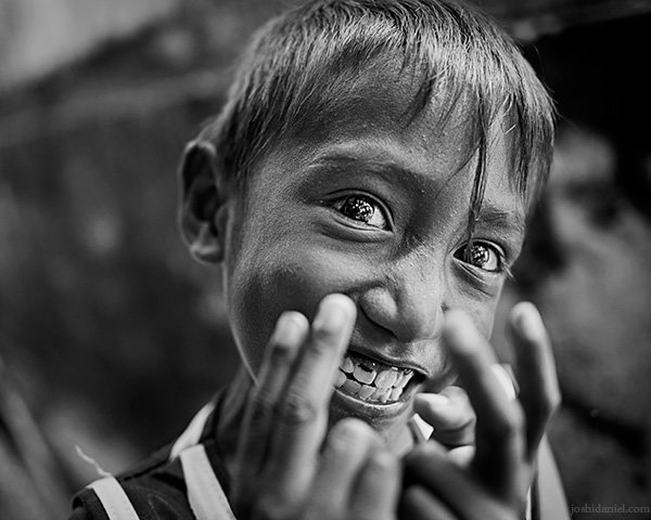 A 28mm wide angle black and white portrait of a young, grinning boy from Rainbow Village, Tual, Maluku, Indonesia