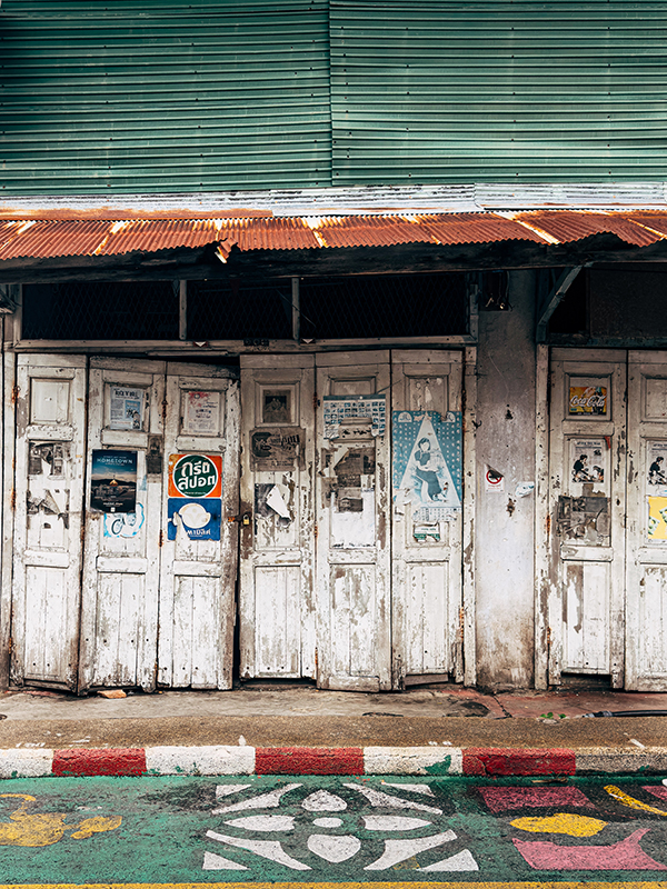 Closed old shopfront with worn posters and textures in Songkhla, Thailand